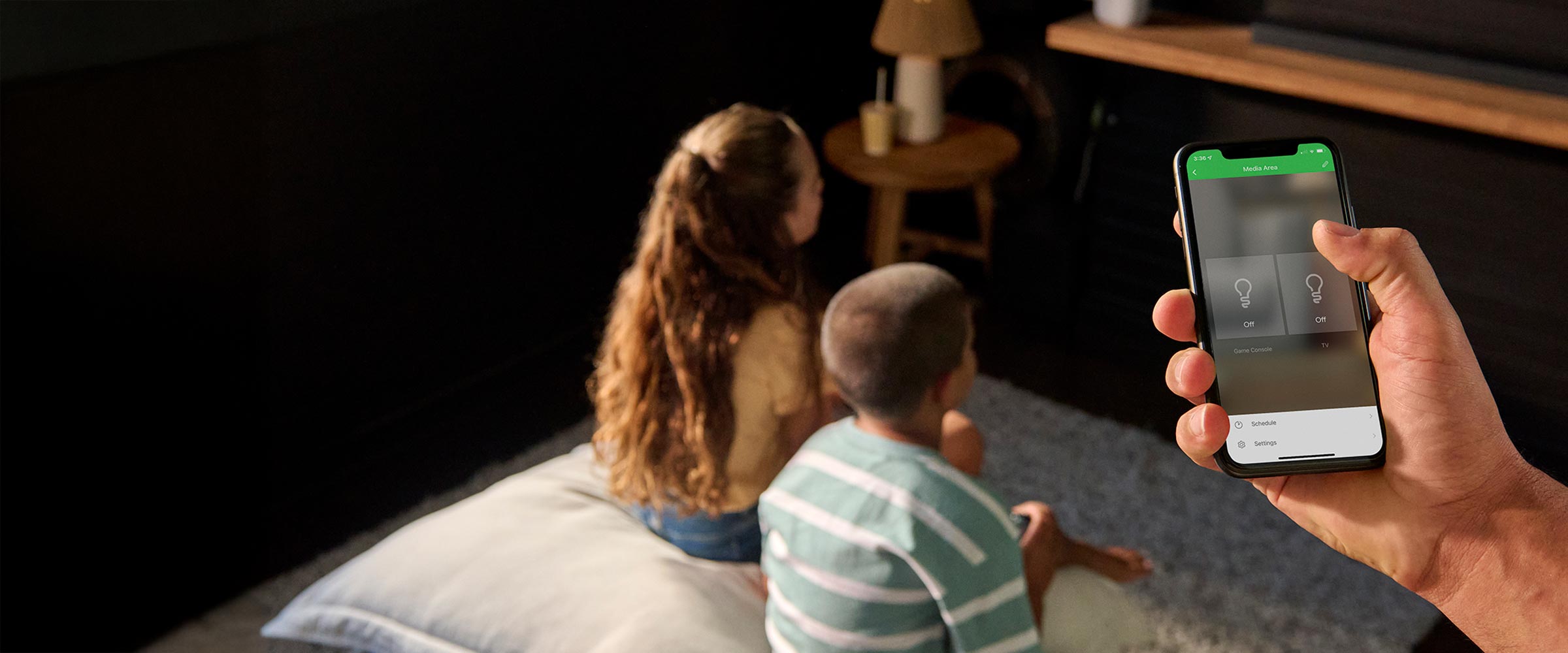 Hand holding a mobile phone in front of children